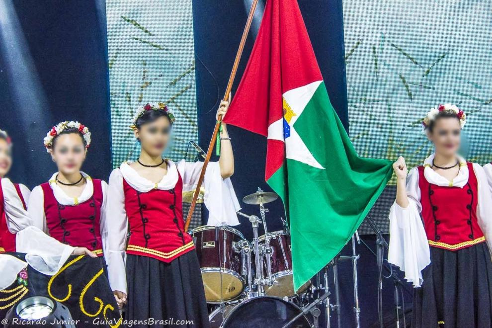 Imagem de meninas vestidas com roupas tipicas italianas e com bandeira de Quiririm.